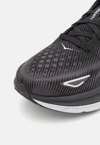 Scarpa da corsa nera con tomaia testurizzata, caratterizzata da un motivo geometrico, dettagli bianchi e una suola ammortizzata per il comfort.