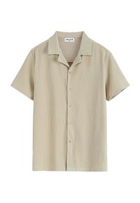 Chemise à manches courtes en tissu côtelé beige clair, avec un col notch et une coupe droite, dotée de six boutons à l'avant.