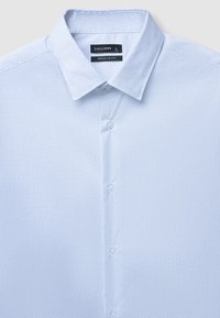 Helles blaues Hemd mit regulärer Passform, mit Kragen und einem Muster aus kleinen, dunklen Punkten. Aus glattem Stoff gefertigt.