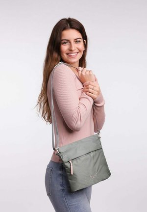 Zelená textilní crossbody taška s růžovým zipem. Hladký povrch, obdélníkový tvar, nastavitelné rameno, přední kapsa a logo.