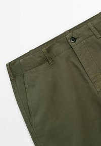 Pantalon vert olive avec fermeture à boutons, passants de ceinture et poches latérales, présenté sur un fond blanc.