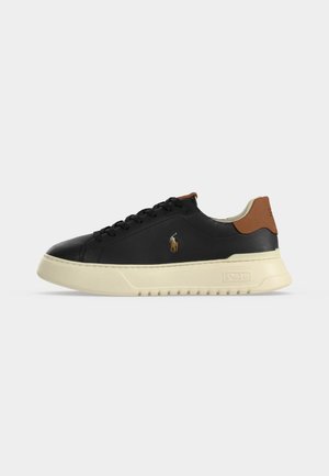 Black low-top leather sneaker with beige sole, brown heel tab, and small embroidered polo player logo on side.