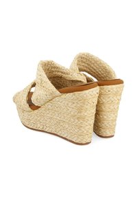 Sandales compensées en paille tissée avec une semelle en cuir beige. Elles présentent un design de brides croisées et une semelle plateforme texturée et surélevée.