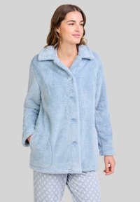 Chaqueta de forro polar de color azul claro y esponjoso, con cuello con muesca, botones frontales y bolsillos laterales. Combinada con pantalones de pijama de estampado.