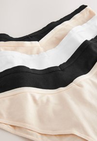 Trzy złożone bezszwowe bawełniane majtki w kolorach beżowym, czarnym i białym, ułożone nałożone na siebie na białym tle.