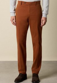 Hnědé bavlněné kalhoty s plochým předním dílem, zapínáním na zip a jedním knoflíkem, s bočními kapsami a upraveným střihem.