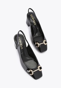 Czarne lakierowane buty na obcasie typu slingback z kwadratowym noskiem, z akcentami w kolorze złotym oraz teksturowaną wkładką. Wysoki blokowy obcas.