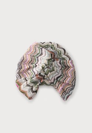 Gestrickte Turbanmütze mit Zickzackmuster in Pink, Grün, Braun, Schwarz und Weiß auf einfarbig hellem Hintergrund.