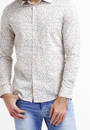 Chemise boutonnée beige clair avec un motif à pois dans différentes nuances de bleu. Conçue avec un col classique et des manches longues.