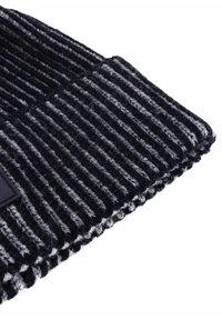 Czapka dziana w ciemnoniebieskie i szare pasy, z prążkowaną fakturą i czarną metką z przodu.