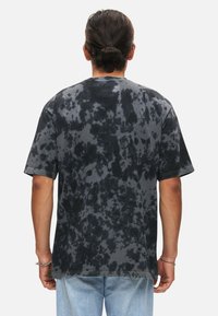 T-shirt a maniche corte in tie-dye nero e grigio con vestibilità rilassata, caratterizzato da un colletto rotondo e dettagli di cucitura in evidenza.