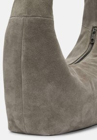 Szare zamszowe botki na koturnie z boku zapinane na zamek, o miękkim, strukturalnym wykończeniu, pokazane w zbliżeniu.