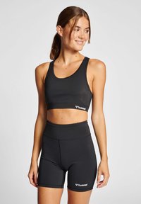 Czarny stanik sportowy z szerokimi ramiączkami oraz pasującymi szortami o wysokim stanie. Oba wykonane z gładkiego, elastycznego materiału z akcentem w postaci logo.