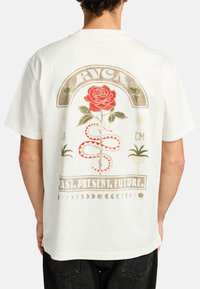 Camiseta blanca de manga corta con un diseño gráfico colorido en la parte posterior, que incluye una rosa roja, una serpiente y el texto: "PASADO. PRESENTE. FUTURO."