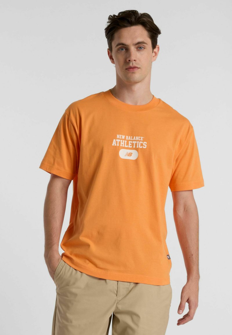 Orange cotton t-shirt featuring "NEW BALANCE ATHLETICS" graphic in white, short sleeves, crew neck, and a relaxed fit.