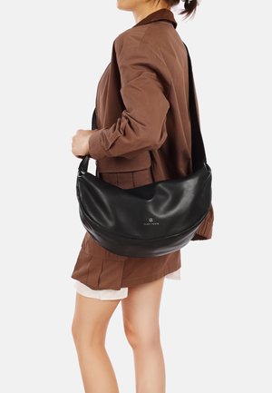 Borsa a tracolla in pelle nera con una texture liscia e un design curvo. Presenta un logo sulla parte anteriore e una tracolla larga e regolabile.