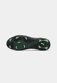 Black and green athletic shoe sole with raised traction studs and Puma logo on a plain white background.