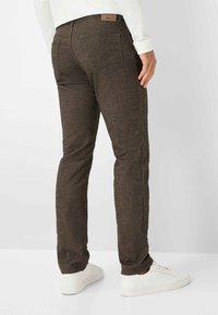 Bruine textuur broek met een rechte snit, voorzien van achterzakken en een gemerkte tailleband, gecombineerd met witte sneakers.