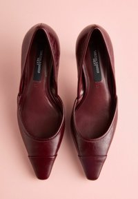 Scarpe in pelle bordeaux con design a taglio basso e punta affusolata. Texture liscia con cuciture visibili e un leggero scintillio.