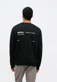 Μαύρο φούτερ με στρογγυλή λαιμόκοψη, απαλή υφή και τυπωμένο κείμενο: «Barbour Weather Comfort» και «South Shields» στην πλάτη.
