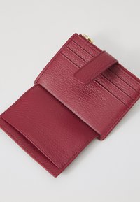 Portafoglio in pelle bordeaux con superficie testurizzata, dotato di più scomparti per carte, una tasca con zip e chiusura a pressione.