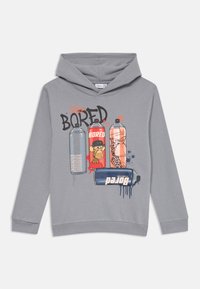 Hoodie gris avec un imprimé graphique représentant des aérosols de peinture, avec des couleurs vives et le texte "STAY BORED" en police grasse. Tissu en mélange de coton.
