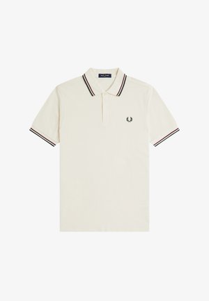 Kermainen pikeepaita lyhyillä hihoilla, kontrastiväriset mustat ja punaiset raidat kauluksessa ja hihansuissa, kaksinappinen aukko ja pieni musta laakerilehtilogo rinnassa.