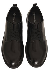 Scarpe di pelle nera con finitura lucida, caratterizzate da puntetonde, chiusura con lacci e suola in gomma testurizzata. Misura 38 riportata all'interno.