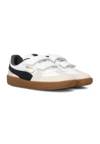 Witte en zwarte sneakers met klittenbandsluitingen. Bovenwerk van suede en synthetisch materiaal, ronde neus en een gestructureerde bruine rubberen zool. Logo-detail zichtbaar.