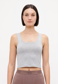 Haut crop gris en tissu doux avec un décolleté carré et des bretelles larges, associé à un legging UGG marron avec une taille logo.