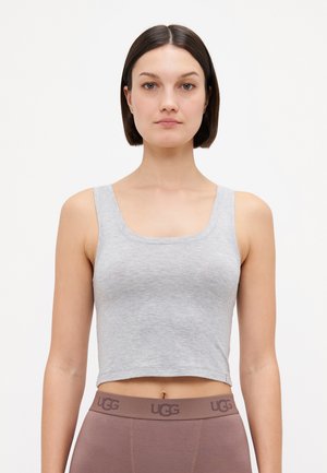 Grå cropped tank topp laget av mykt stoff med firkantet halsringning og brede stropper, kombinert med brune UGG leggings med logo i livet.