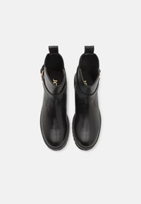 Botas de tobillo de cuero negro con acabado suave, paneles laterales elásticos, tiradores y una suela de goma texturizada para mayor agarre. Logo dorado en el interior.