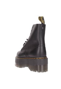 Bottine en cuir noir avec une semelle épaisse et translucide, un devant à lacets et une languette jaune à l'arrière. Détails texturés sur la semelle.