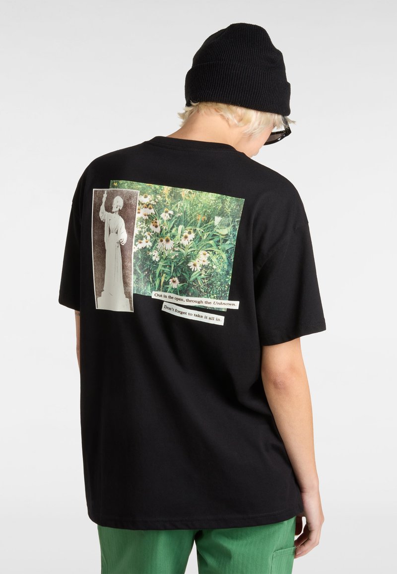 Sort bomulds t-shirt med et stort grafisk motiv på ryggen, der viser to billeder: en statue og en blomsterscene, ledsaget af tekstoverskrifter.