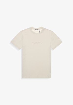 Camiseta de algodón, color beige claro, cuello redondo, mangas cortas, presenta el logotipo emblema "MORATO" en la parte frontal, textura suave.