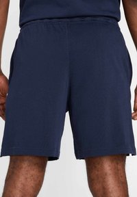 Pantalones cortos deportivos de color azul marino con cintura elástica, bolsillos laterales y una textura suave, adecuados para el uso activo o casual.