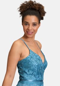 Niebieska sukienka z misterną kwiatową haftem, cienkimi ramiączkami, głębokim dekoltem i płynną spódnicą o gładkiej fakturze.