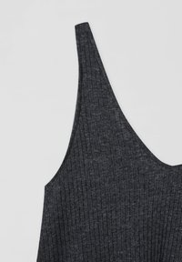 Tissu tricot côtelé gris foncé, formé en un haut sans manches à fines bretelles ou une partie de robe sur un fond uni clair.