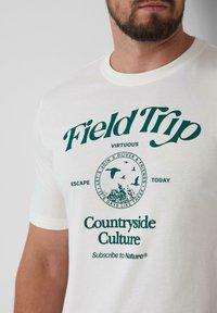 Witte katoenen t-shirt met groene grafische tekst en een circulair natuurthema-ontwerp. Korte mouwen en een ronde halsstijl.