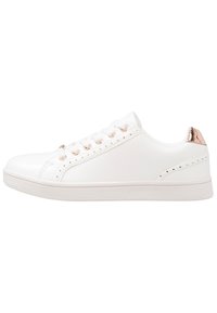 Vita sneakers i syntetmaterial. Har rund tå, platt sula, sex snörhål och en metallisk roséguldfärgad detalj på hälen.