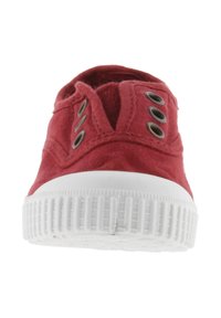 Sneaker di tela rossa con occhielli metallici, suola in gomma bianca e motivo antiscivolo testurizzato sulla parte inferiore. Design low-top con punta arrotondata.