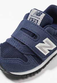Tmavě modré boty New Balance 373 z veluru a síťoviny, zapínání na suchý zip, světle šedé logo a texturovaná gumová podešev.