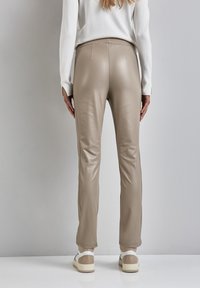 Tan nep leren broeken met een slim fit, voorzien van een hoge taille, een gladde textuur en achterseams. Gecombineerd met lichtgekleurde schoeisel.