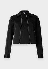 Veste courte noire en tissu lisse et léger. Elle comporte une fermeture éclair à l'avant, des poches latérales et un col classique.