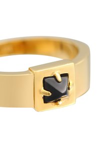 Gold ring with a wide band and a square front featuring a black enamel accent shaped like a pointed arrow. Smooth finish and polished texture.