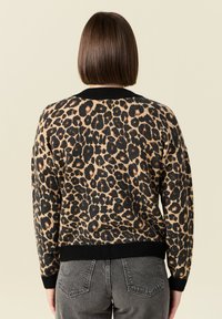 Maglione con stampa leopardata, colletto e polsini a coste neri, caratterizzato da una texture morbida e una vestibilità comoda, abbinato a pantaloni grigi.