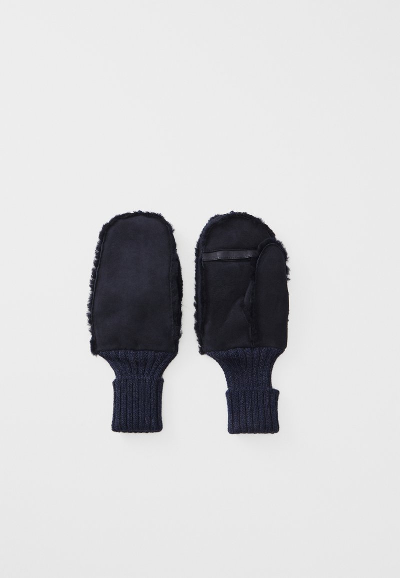 Marinefargede votter laget av myk stoff med faux pelsfôr og ribbestrikkede mansjetter. Har en enkelt lærdetalj på høyre votten.