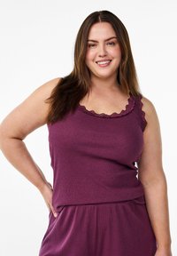 Purple sleeveless top with a textured fabric, featuring a scalloped lace neckline and a relaxed fit. Model poses with one hand on hip.