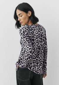 Bluză cu mânecă lungă, imprimeu leopard în nuanțe de violet deschis și negru; material moale, guler rotund și șlițuri laterale la tiv pentru ușurința în mișcare.