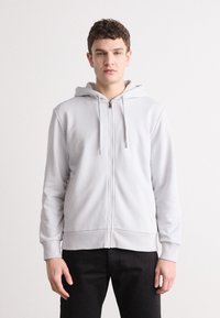 Casaco de capuz cinza-claro com fecho, feito de material suave, apresentando punhos e barra canelados, e um design frontal simples.